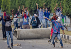 A Kashmiri Muslim protester throws stones at Indian troops as others shout pro freedom slogans in Srinagar, Indian controlled Kashmir, Tuesday, July 12, 2016. Clashes between Indian troops and protesters continued for fourth consecutive day despite a curfew imposed in the disputed Himalayan region to suppress anti-India violence following the Friday killing of Burhan Wani, chief of operations of Hizbul Mujahideen, Kashmir's largest rebel group. (AP Photo/Dar Yasin)